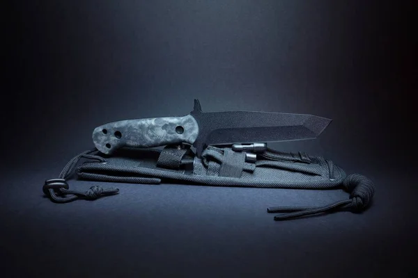 A large outdoor knife with a tanto blade on a black background.