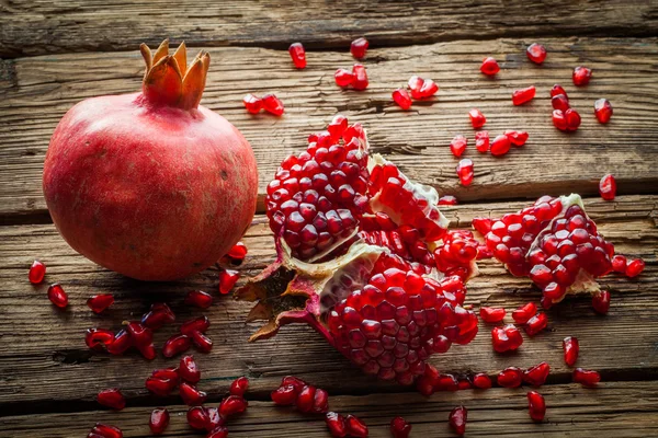 Juicy pomegranate fruit over wooden table — Stock Photo, Image