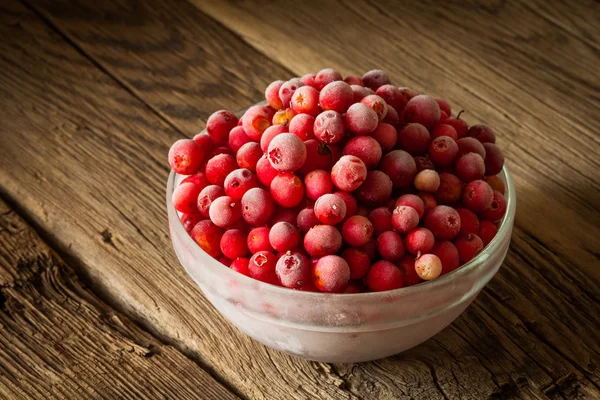 Frozen cranberry in bowl on wooden background — Stock Photo, Image