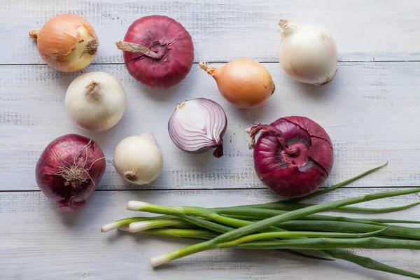 Sortierte Bauernhof frische Zwiebeln auf einem Holztisch mit Frühlingszwiebeln — Stockfoto
