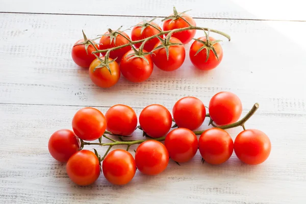 Červená rajčata na dřevěný stůl — Stock fotografie