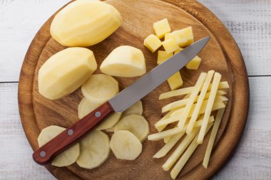 RAW soyulmuş ve dilimlenmiş patates kesme tahtası üzerinde 