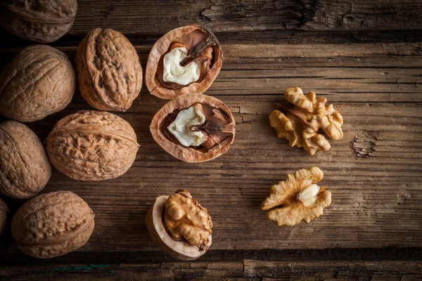 Walnotenpitten en hele walnoten op oude houten tafel — Stockfoto