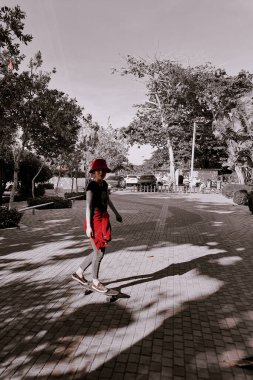 Sahilde güneş ışığı altında kırmızı ceketle kaykay yapmak.