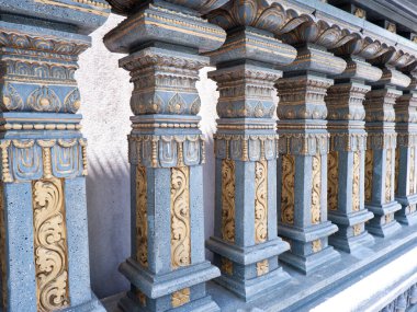 Güneşli bir günde altın ve gri sütunlu Hindu tapınağı duvarı