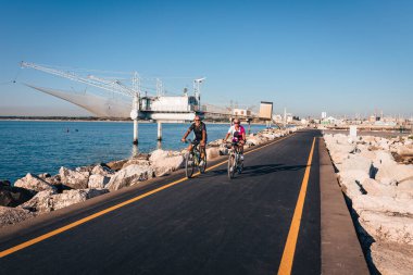 Marina di Ravenna, Emilia Romagna - İtalya Ağustos 2020: Yazın Zaccagnini rıhtımında bisiklet süren çift