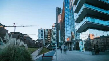 Günbatımında gökdelenlerin altında yürüyen insanlar, Milan, İtalya, zaman ayarlı, 4K