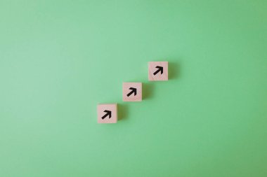 Büyümeyi simgeleyen siyah okları olan üç tahta küp. Yeşil arkaplan, kopyalama alanı