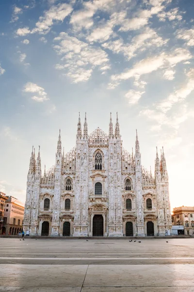 Milan, İtalya - Mart 2021: Coronavirüs ablukası nedeniyle boş bir kareyle Milano Katedrali 'nin manzarası, mavi gökyüzü, beyaz bulutlar ve yeni doğan güneşten parlayan ışık,