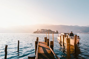 Orta San Giulio, İtalya - Aralık 2020: Orta Gölü 'ndeki San Giulio adasının turist teknesiyle görüntüsü