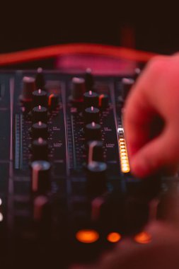 Milan, İtalya - 15 Haziran 2024: Bir müzik performansı sırasında dinamik canlı ses ayarlarını gösteren DJ mikseri üzerindeki elleri kontrol etmek.