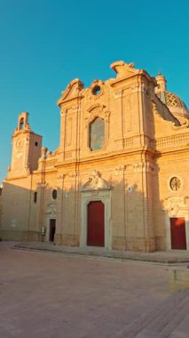 Oria, Apulia, İtalya - 17 Ağustos 2025: Oria 'daki Santa Maria Assunta Katedrali' nin ön cephesinin dikey 4K görüntüsü, tarihi kent merkezinde sıcak yaz ışığı ile aydınlatılmıştır..