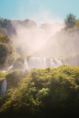 Marmore, İtalya - 19 Ağustos 2025: Yeşil yaprakların arasından görülen şelale doğal bir çerçeve oluşturuyor.