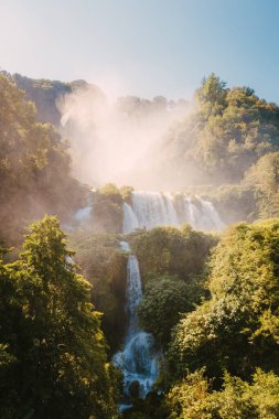 Marmore, İtalya - 19 Ağustos 2025: Açık mavi yaz gökyüzü ve parlak güneş ışığı altında Cascata delle Marmore 'un geniş manzarası.