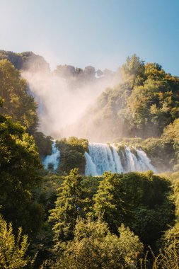 Marmore, İtalya - 19 Ağustos 2025: Cascata delle Marmore 'un yükselen sisli ve yemyeşil ormanlı panoramik manzarası yaz güneşi altında.