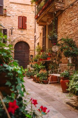 Spello, İtalya - 18 Ağustos 2025: Dokulu taş duvarlar ve tarihi merkezde mimari temalar için uygun ahşap kapılar tarafından çerçevelenmiş uzun dar geçit.