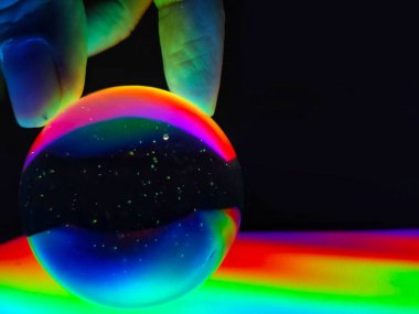 Siyah arka planda üç parmağı izole bir şekilde kristal küreyi yakan renkli bir el..