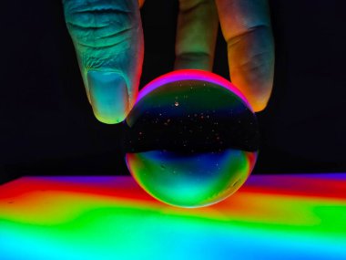 Siyah arka planda üç parmağı izole bir şekilde kristal küreyi yakan renkli bir el..