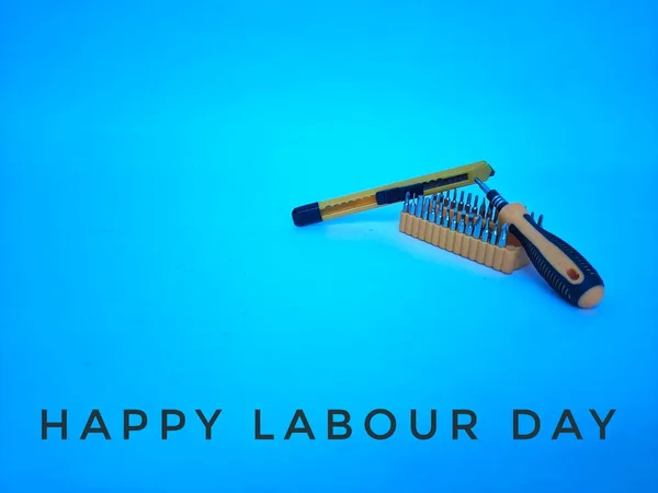 \'Happy Labour Day\'quote with a set screw driver bit and knife isolated on blue background.
