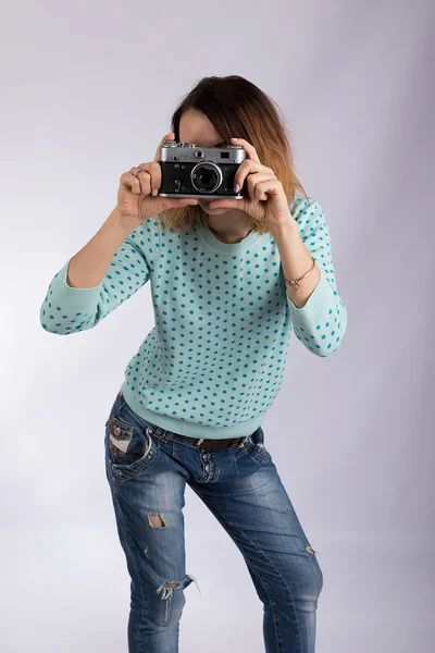 Het meisje met de camera, in een blauwe trui en jeans. — Stockfoto