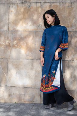 Genç Vietnamlı model kız gülümsüyor geleneksel mavi elbiseyle Madrid sokaklarında turuncu ve sarı detaylarıyla doğal ve spontane bir şekilde dans ediyor.