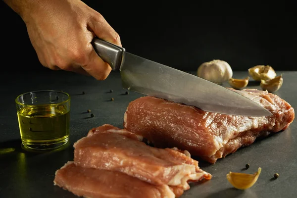 ナイフで男性の手は スパイスの横にある石灰色の背景に生の新鮮な肉の大部分をカット — ストック写真