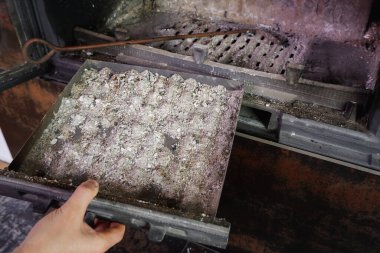 Şömine temizliği. Adam kürekle kürek tutuyor. Bir el şöminenin küllerini eski çelik bir bıçakla topluyor. Günlük kış rutini