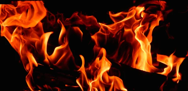 暖炉で薪を燃やす熱い オレンジの炎 黒を背景にした火の舞 — ストック写真