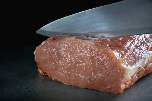 シェフは新鮮な生肉をステーキにカットしています 灰色の背景でのクローズアップ — ストック写真