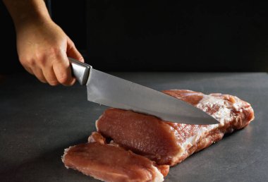 Şef taze çiğ eti bifteğe çeviriyor. Gri arkaplanda yakın plan.