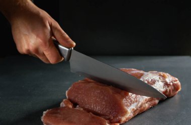 Şef taze çiğ eti bifteğe çeviriyor. Gri arkaplanda yakın plan.