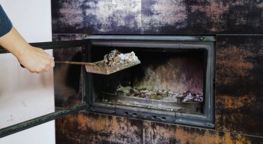 Şömine temizliği. Bir kadın kürekle kürek tutuyor. Bir el şöminenin küllerini eski çelik bir bıçakla topluyor. Günlük kış rutini