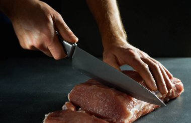 Şef taze çiğ eti bifteğe çeviriyor. Gri arkaplanda yakın plan.