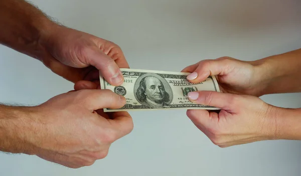 Man passing banknote to woman. Paper money in hand. Two hands of young woman or man holding 100 USD on white background.