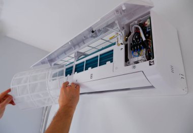 Klimanın bakımı. Bir teknisyen filtreyi temizliyor. Ellere bak..