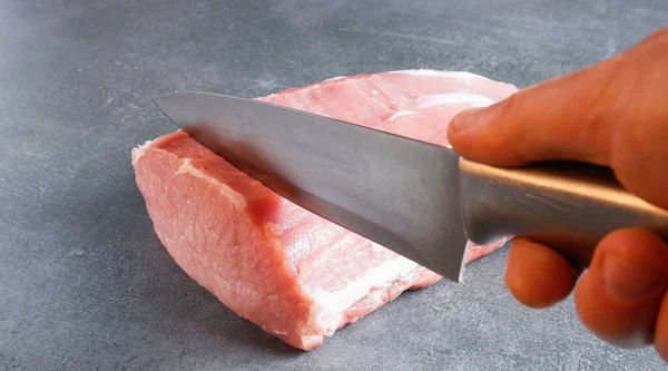 生肉だ シェフは灰色の背景にナイフで食欲をそそるキューボールをカットします — ストック写真