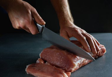 Şef taze çiğ eti bifteğe çeviriyor. Gri arkaplanda yakın plan.