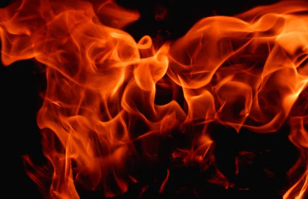 暖炉の抽象的な火の炎 背景の質感 夜の闇の中で美しく明るいオレンジ色の炎がちらつきます — ストック写真