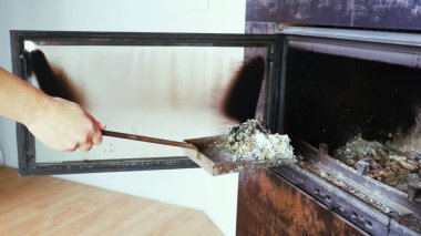 Şömine temizliği. Bir kadın kürekle kürek tutuyor. Bir el şöminenin küllerini eski çelik bir bıçakla topluyor. Günlük kış rutini