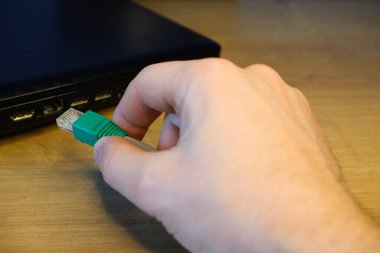 Bir kadının eli bir RJ45 ağ bağlantısını laptopa bağlar..