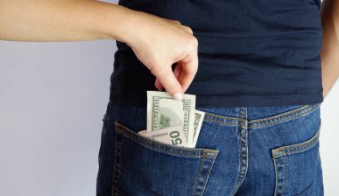 Kadın, ayakta duran adamın kot pantolonunun arka cebinden para çıkarıyor. Ellerin yakın görüntüsü. Metnin için yer.