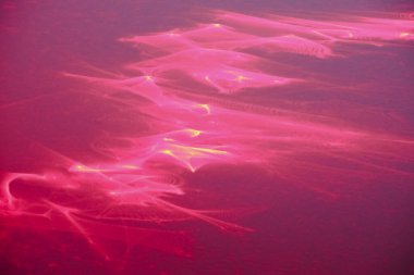 Soyut fraktal ışık arkaplan fotoğrafı. Kırmızı, turuncu, altın rengi ışık, ışınlar, koyu arkaplanda şekiller. Arkaplan fotoğrafı lazer ışınları kırılarak çizildi.