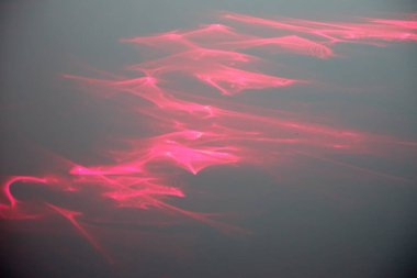 Soyut fraktal ışık arkaplan fotoğrafı. Kırmızı, turuncu, altın rengi ışık, ışınlar, koyu arkaplanda şekiller. Arkaplan fotoğrafı lazer ışınları kırılarak çizildi.