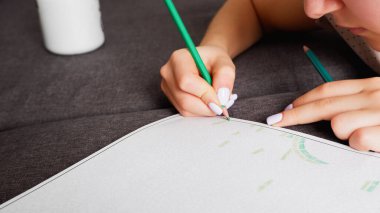 Kız çok renkli kalemlerle bir boyama yapıyor, yakın plan çekimde. Ev sanatı hobisi.