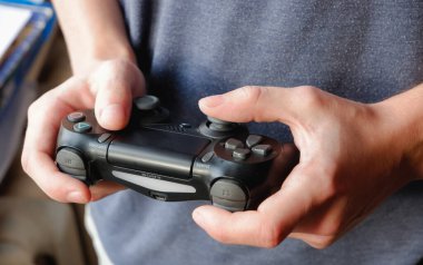 KYIV, UKRAINE - Mart 03 2021: SONY PlayStation 4 oyun alanı. Genç bir çocuğun elinde siyah bir av alanı fotoğrafı var..