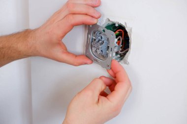 Bir adam aydınlatma düğmesini tamir eder. Yakından çek. Elektrikçi işi..