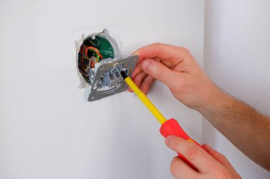 Elektrikçi anahtarı tornavidayla söker. Ellere yakın çekim. Bir elektrikçinin rutin işi. Bağlantıları kontrol ediyorum. Değiştir.