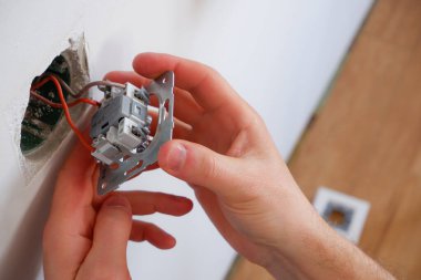 Bir adam aydınlatma düğmesini tamir eder. Yakından çek. Elektrikçi işi..