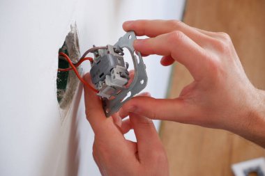 Bir adam aydınlatma düğmesini tamir eder. Yakından çek. Elektrikçi işi..