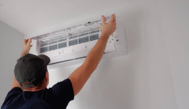 Klima tamiri ve bakımı. Teknisyen, temizlik için iç mekan ünitesinin filtresini kaldırır..